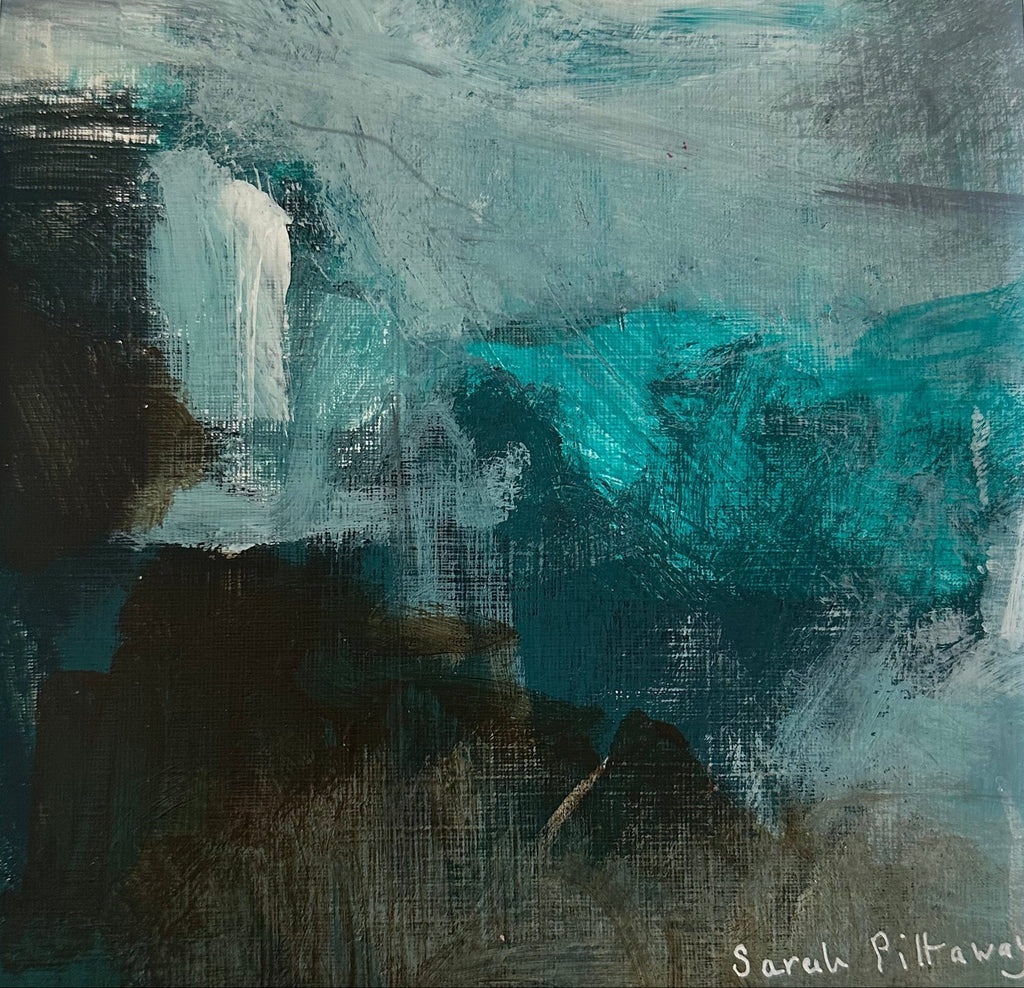A square framed abstract painting featuring teal, blue, black, and white brushstrokes, housed in a white frame on a light gray marble surface.