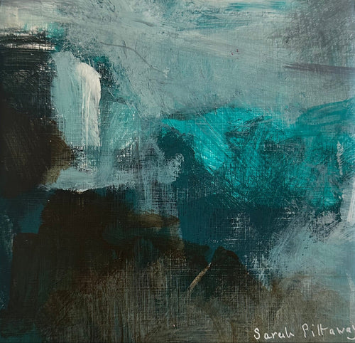A square framed abstract painting featuring teal, blue, black, and white brushstrokes, housed in a white frame on a light gray marble surface.