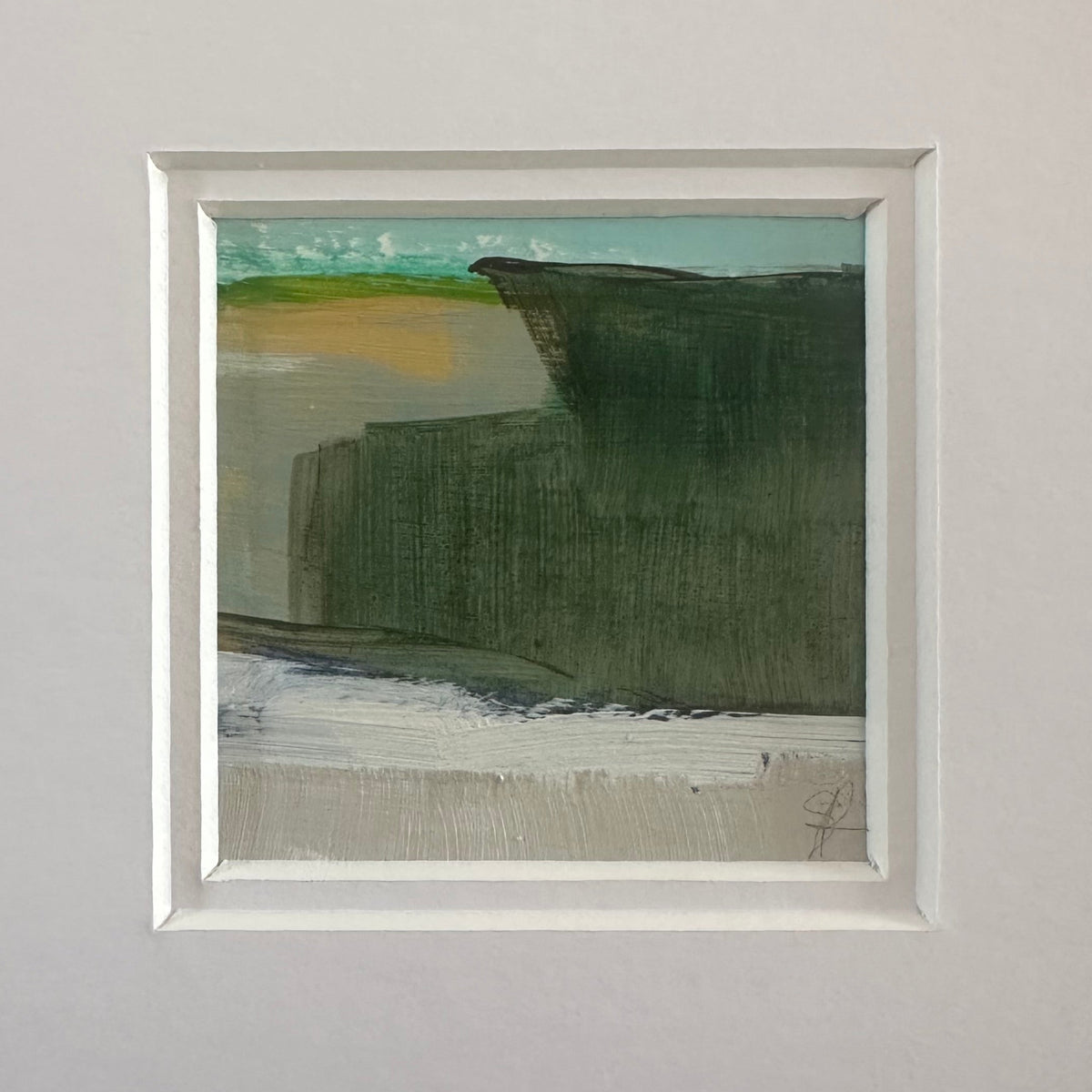 A framed abstract landscape painting featuring shades of green, brown, and gray, presented with a wide white mat board against a textured gray wall.